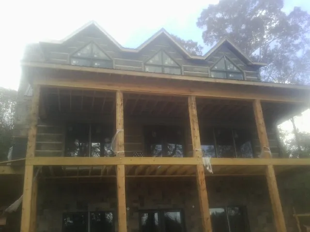 Dormers and porch framing on a large log home under construction — Roof Coating work by our crew in Mount Olive