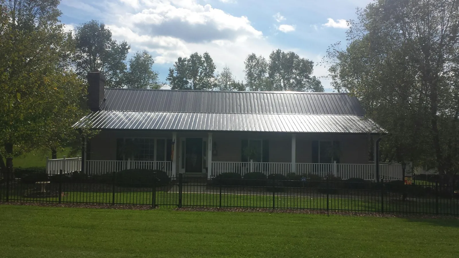 Gray metal roof on a brick ranch with a full width front porch — Gutter Guard Installation work by our crew in Mount Olive