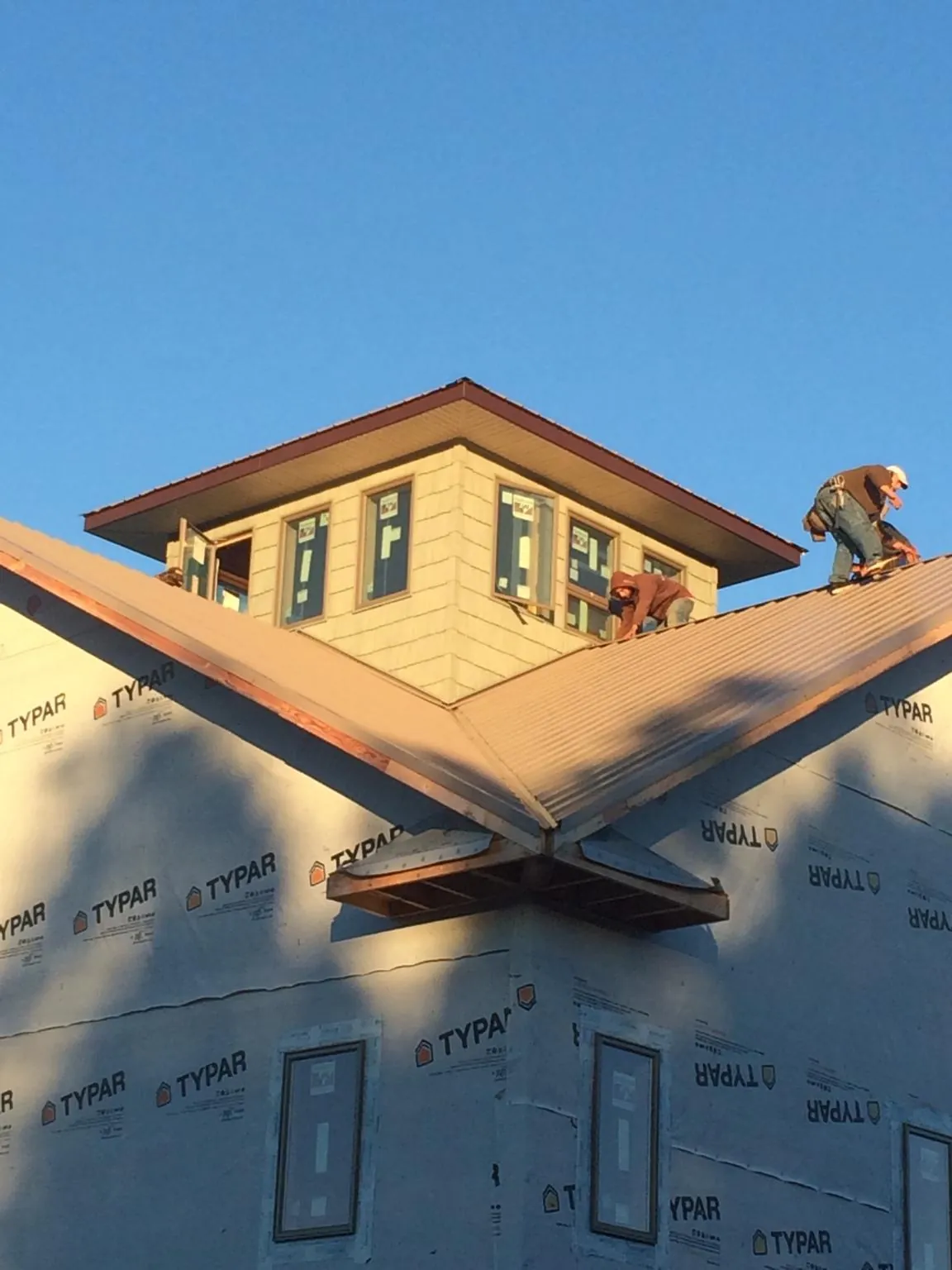 Roofers working around a rooftop cupola on a new metal roof at sunset — Roof Waterproofing in Mount Olive by Roofing Brothers